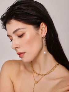Dettaglio della collana a cuore dorata e orecchini di perle indossati dalla modella
