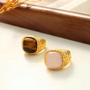Detail of square tiger eye and pink stone rings with vintage textured gold finish