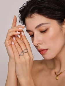 Detailed view of layered colorful zircon rings and a gold locket necklace on a model