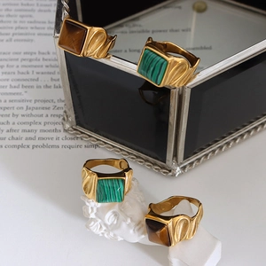 Vintage gold square rings with tiger eye and malachite gemstones set on a white sculpture