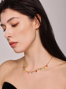 Close-up of a gold choker necklace with colorful enamel heart charms on a female model