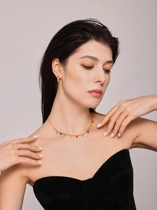 Detail of colorful faceted crystal stone necklace and gold hoop earrings on model