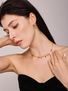 Detail of gold necklace with multi-colored crystal stones on a model's collarbone