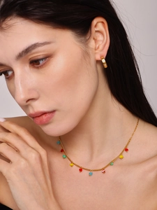 Detail of colorful heart charms necklace and gold hoop earrings on a female model