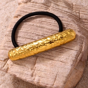 Détail de la décoration métallique martelée plaquée or 18K sur un élastique à cheveux noir