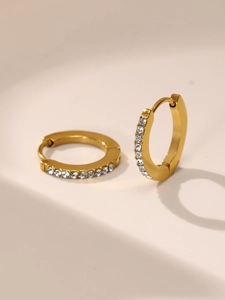 Dettaglio di orecchini a cerchio dorati con zirconi incastonati per un look chic