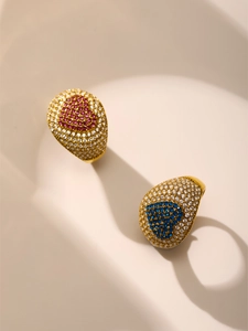 Details von vergoldeten Ringen mit Zirkonia und roten sowie blauen Edelsteinherzen