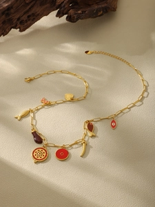 Detailed view of gold multi-pendant necklace with colorful eye and fish charms on beige