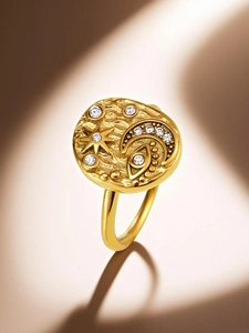 Macro shot of gold celestial ring with engraved star, moon, and eye icons with cubic zirconia