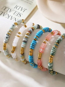 Detailed shot of six multi-colored beaded bracelets with golden metal spacers on display