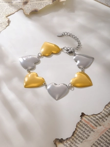 Detalle de la pulsera de eslabones de corazón en dos tonos oro y plata con cierre de mosquetón