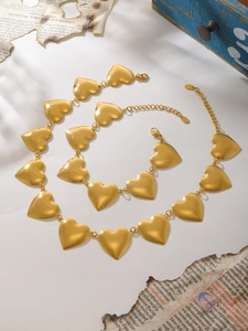 Vista detallada del conjunto de collar y pulsera con eslabones de corazón sobre papel retro