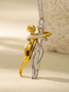 Macro view of two-tone gold and silver embrace pendant on a delicate chain necklace