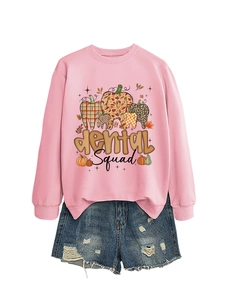 Flat lay of pink dental Squad sweatshirt featuring autumn pumpkin teeth pattern and denim shorts