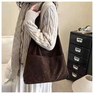 Detail of dark brown suede tote bag with front pockets styled in a retro autumn look