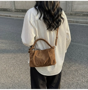Detail of vintage brown suede small square bag with pleated texture and silver hardware