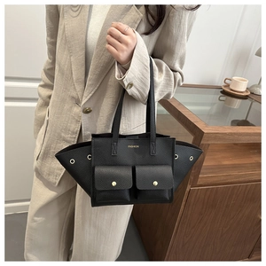 Detail of black pebbled leather tote bag with gold buckle pockets and side wing design