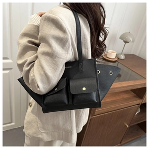Detail of black pebbled leather tote bag featuring wing design and gold button pockets