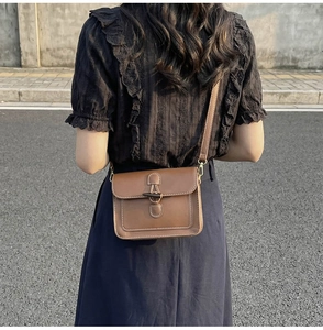 Close-up of brown vintage crossbody bag with wooden toggle closure and contrast stitching