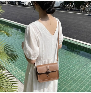Detail view of brown vintage leather crossbody bag with metal buckle on a model