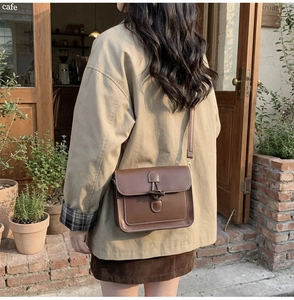 Detail of vintage brown tote bag with horn buckle shown on model in cafe setting