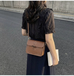 Detail of vintage brown leather tote bag with white contrast stitching and buckle closure