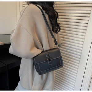 Detail of black wax leather tote with contrast white stitching and metal horn buckle