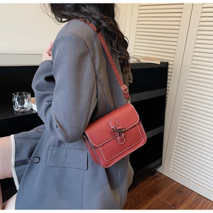 Detailed side view of brick red leather tote bag with white contrast stitching and horn buckle