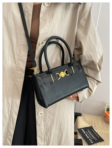 Detailed look at a black leather square handbag with golden heart hardware and handles