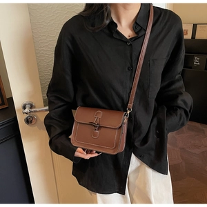 Close-up of vintage brown leather crossbody bag with toggle closure and white contrast stitching