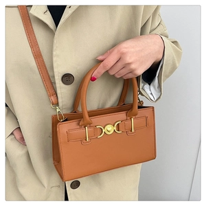 Detail showing the brown faux leather bag with a gold heart clasp and top handle