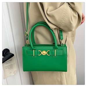 Detail of emerald green faux leather square bag with gold heart clasp and strap