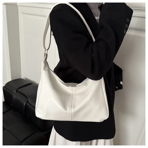 Detail of white textured leather hobo bag featuring vertical stitching and a wide strap