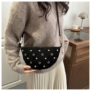 Detail of black suede half-moon bag with gold studs and metal ring hardware accents