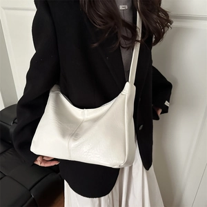 Minimalist cream white hobo bag with leather texture worn over the shoulder