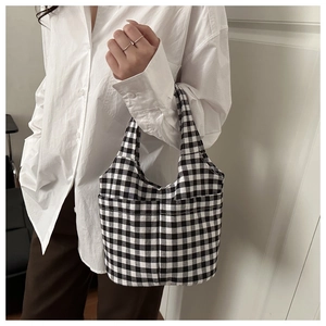 Close-up of black and white gingham canvas tote bag featuring a practical side pocket detail