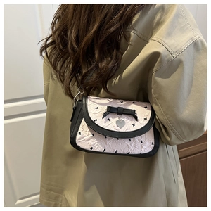 Détail du sac selle rose avec motif à nœuds et pendentif métallique en forme de cœur