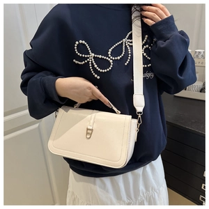 Détail d'un sac à bandoulière crème avec boucle dorée et large sangle en tissu