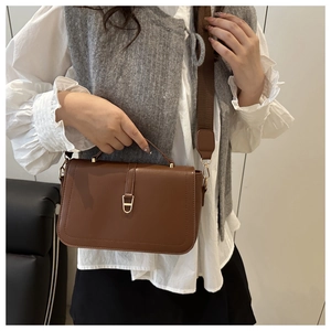 Détail d'un sac carré en cuir marron avec fermoir métallique en forme de bouclier