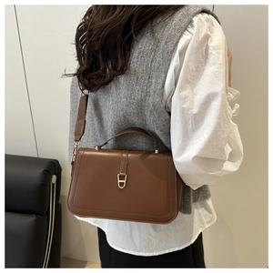 Détail du sac à bandoulière en cuir marron foncé avec boucle dorée en forme de D