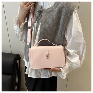 Detailed shot of a pale pink glossy leather bag featuring a gold metal lock and wide strap