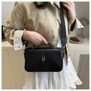 Détail du sac bandoulière en cuir noir minimaliste avec fermoir doré et sangle large