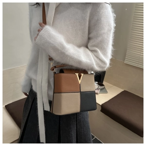 Detail of color-block bucket bag with gold V-hardware and textured pebble leather