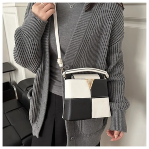 Close-up of contrast checkerboard bucket bag with V-shaped gold hardware and lychee grain leather
