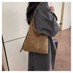 Close-up of brown suede tote bag featuring white contrast stitching and silver hardware detail