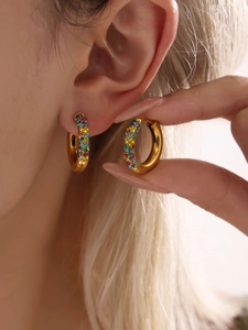 Close-up of gold hoop earrings with multi-color cubic zirconia rainbow stones