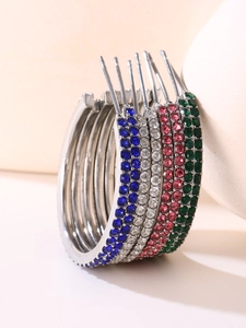 Macro shot of silver C-shape earrings with cubic zirconia in blue, pink, and green
