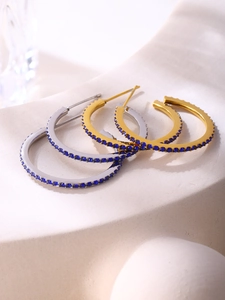 Macro detail of gold and silver hoop earrings featuring pavé set dark blue cubic zirconia