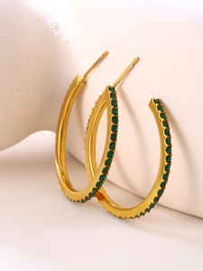 Detail of gold C-shaped hoop earrings with micro-set deep green cubic zirconia crystals