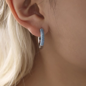 Polished silver hoop earrings featuring pavé set turquoise zircons on a female model